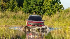 a red 2021 Ford Bronco driving through shallow water