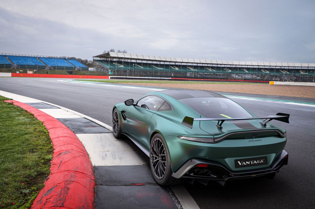 The rear 3/4 view of a green-and-black 2022 Aston Martin Vantage F1 Edition on a racetrack corner