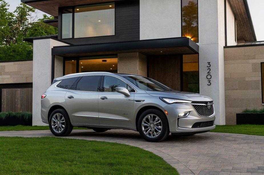 A silver 2022 Buick Enclave Avenir luxury midsize SUV parked in front of a modern house