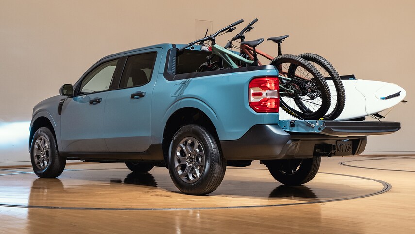 a blue 2022 ford maverick with bikes and a surf board in the bed 