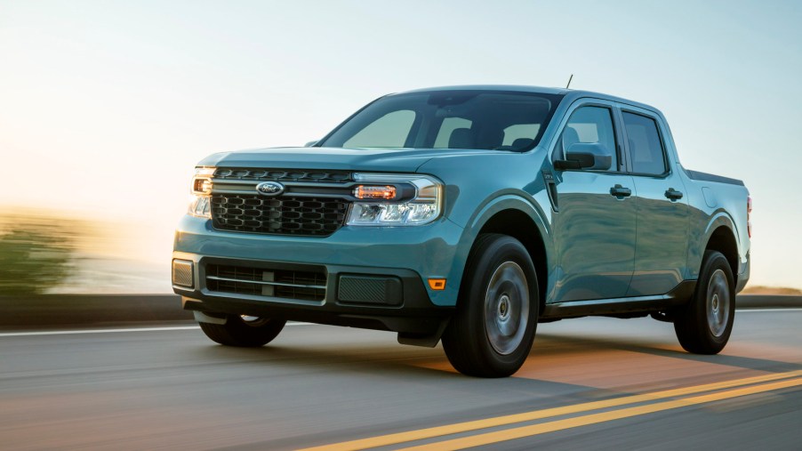 A powder-blue 2022 Ford Maverick Hybrid XLT compact pickup truck travels on a two-lane highway