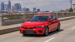 A red 2022 Honda Civic Sedan Touring drives down a city highway