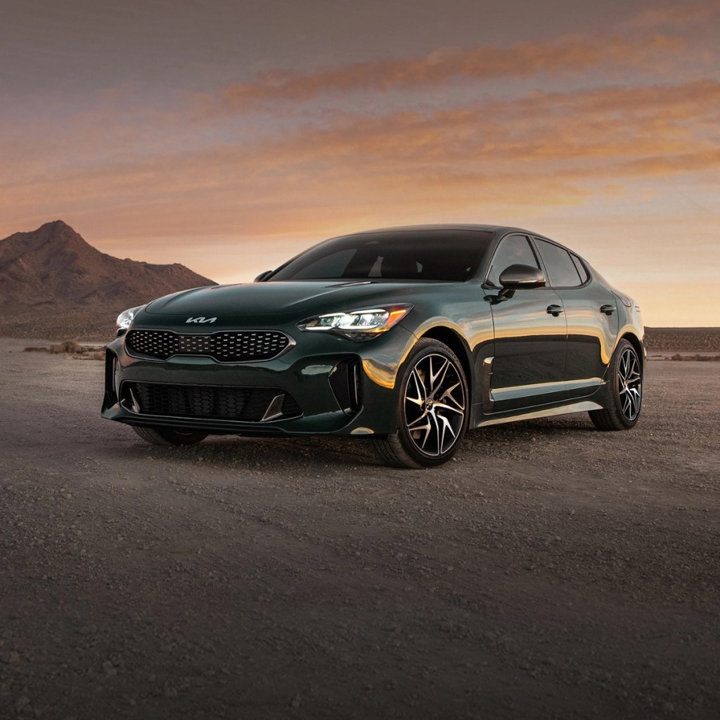 A dark colored 2022 Kia Stinger sits on a dirt road with a small hill behind it. The 2022 Kia Stinger is an IIHS Top Safety Pick+.