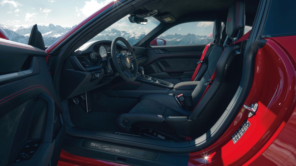 The black interior and carbon-fiber bucket seats of a red 2022 Porsche 911 Carrera GTS Coupe interior with the Lightweight Package