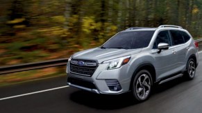 A gray 2022 Subaru Forester small SUV is driving on the road.
