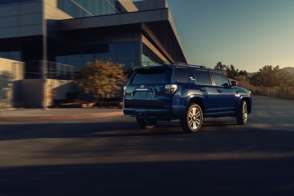 The rear 3/4 view of a dark-blue 2022 Toyota 4Runner TRD Sport driving around the corner of a building
