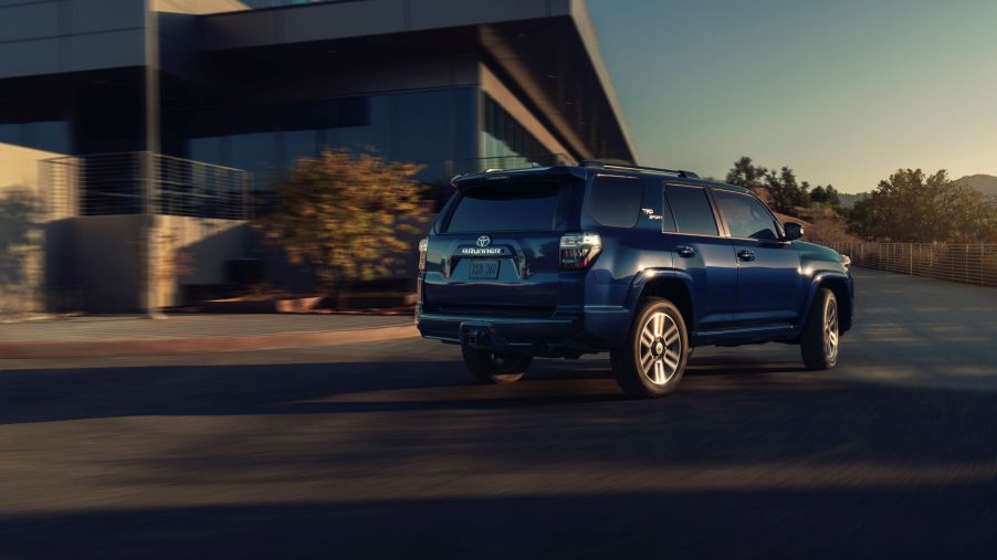 The rear 3/4 view of a dark-blue 2022 Toyota 4Runner TRD Sport driving around the corner of a building