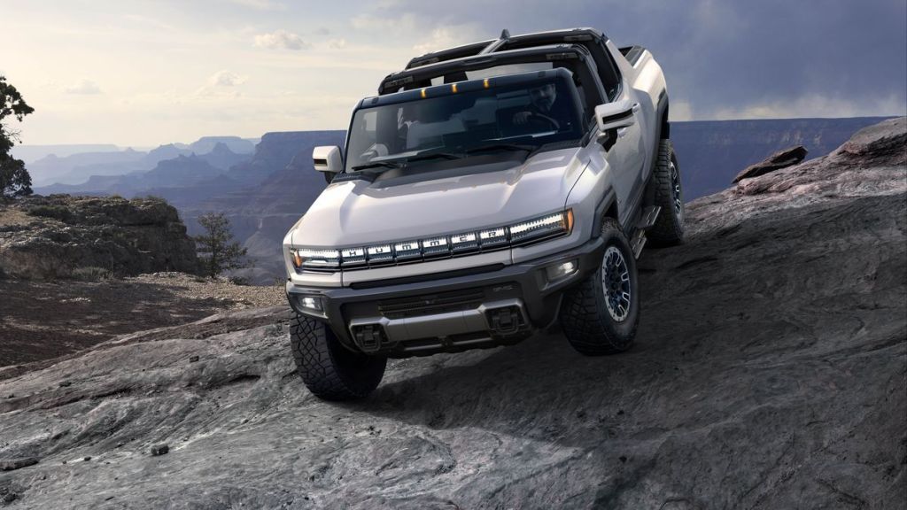 The 2022 GMC Hummer EV truck driving down a large rock