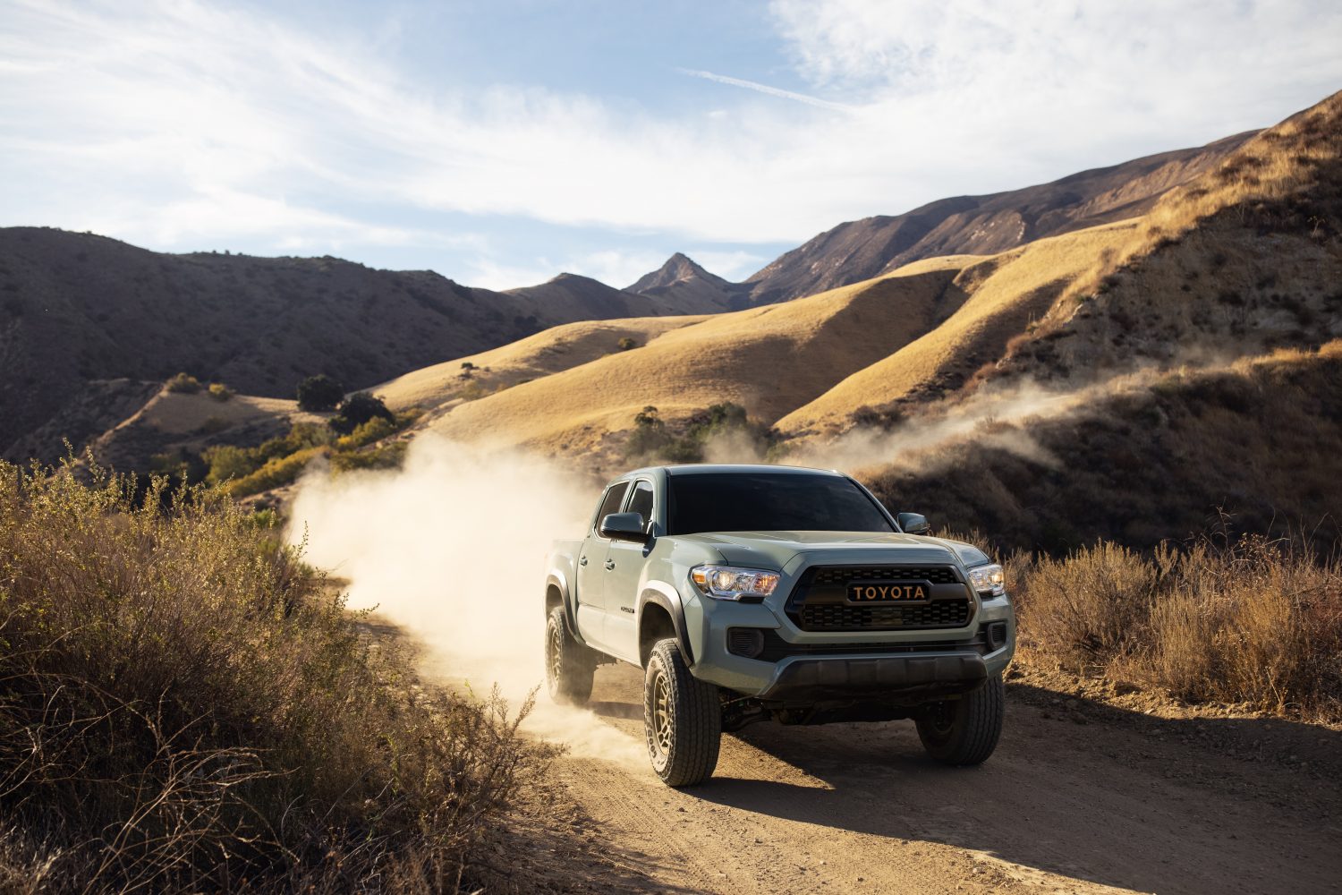 A 2022 Toyota Tacoma Trail Edition on a dusty mountain trail kicking up dirt
