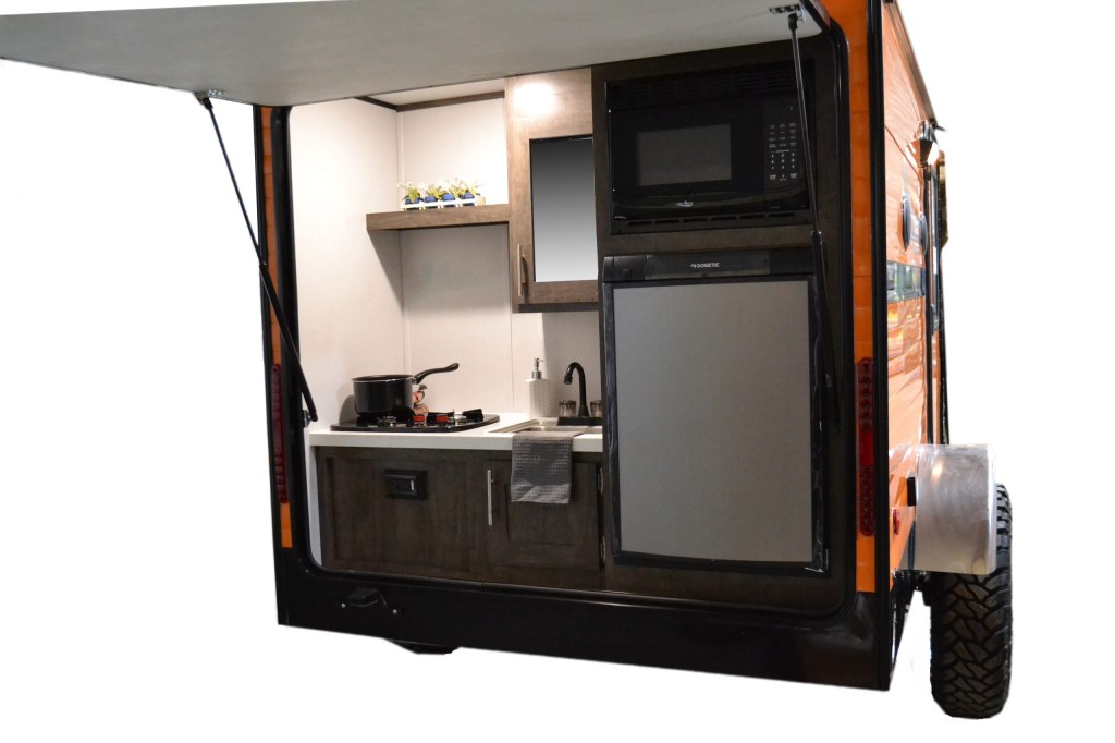 the rear of the retro RV camper trailer showing the kitchen beneath a fold out awning that doubles as a rear hatch. 