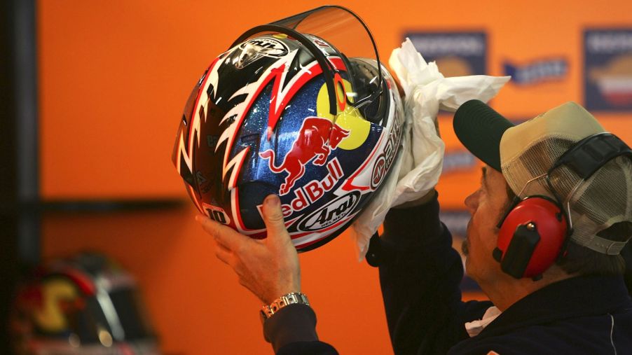 A Repsol Honda MotoGP mechanic cleaning a motorcycle helmet for Nicki Hayden at the 2006 Shanghai GP