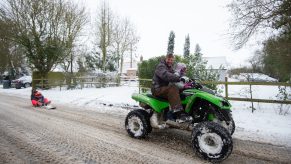 Richard Squirrell uses a quad bike to give his granddaughters a ride in the snow in Wattisham in Suffolk, with heavy snow set to bring disruption to south-east England
