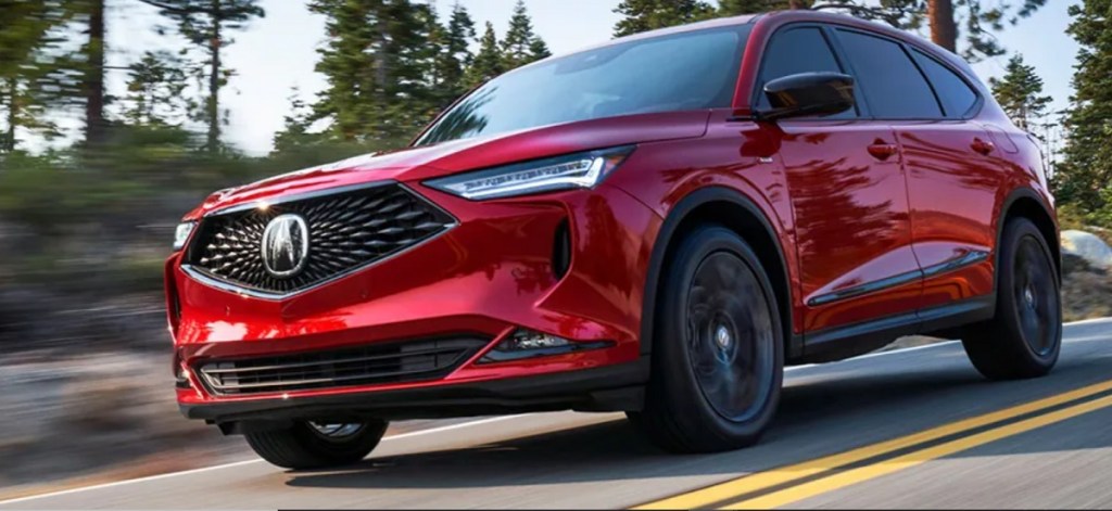 A red 2022 Acura MDX races down a wooded road.
