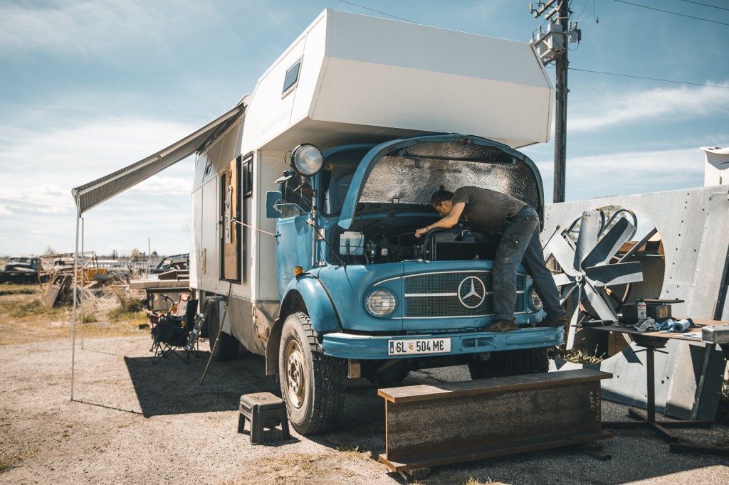 Man working on his vintage Mercedes camper van in the desert