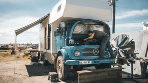 Man working on his vintage Mercedes camper van in the desert