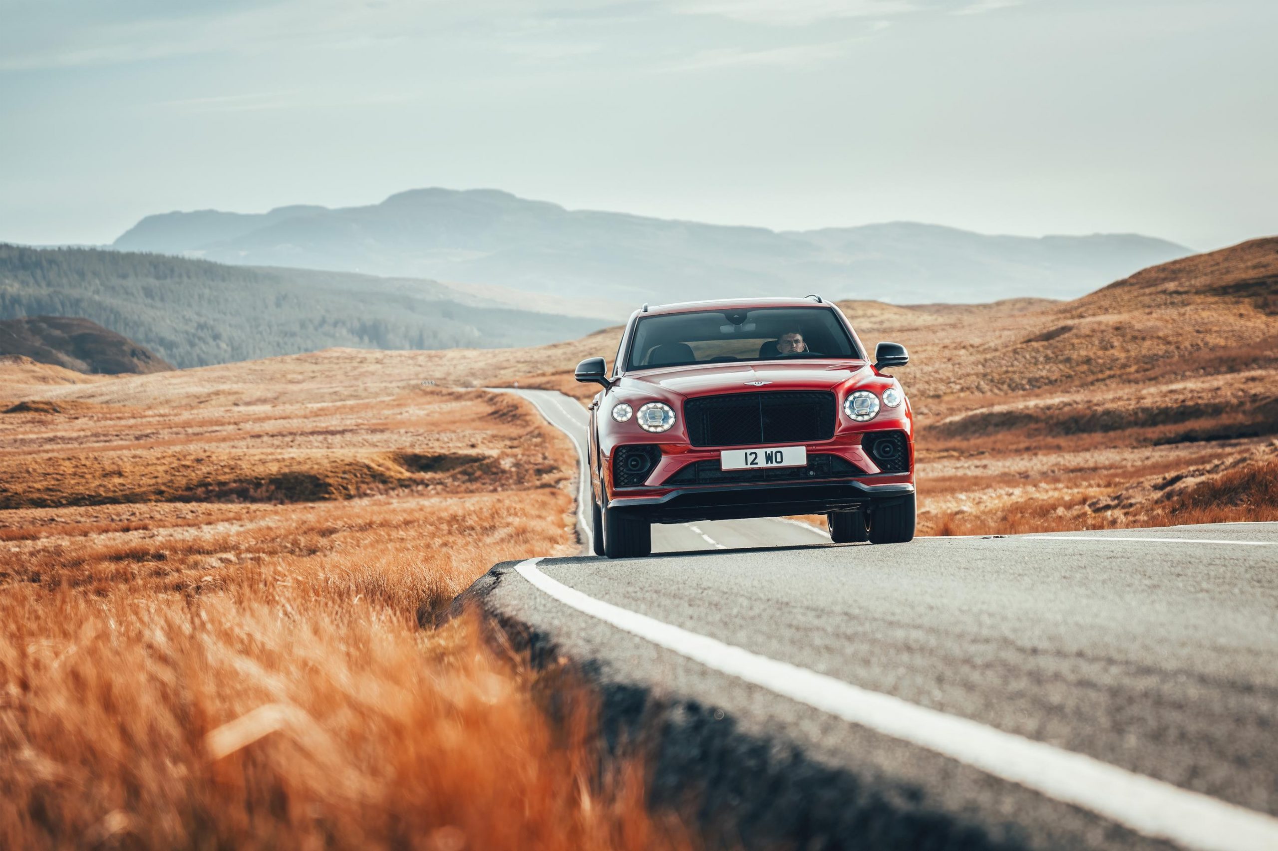 A red Bentley Bentayga S on a twisty back road