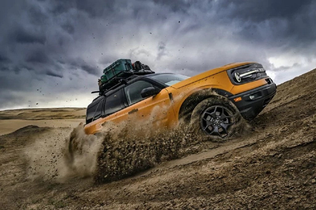 A yellow 2021 Ford Bronco Sport drives up a dirt hill. 