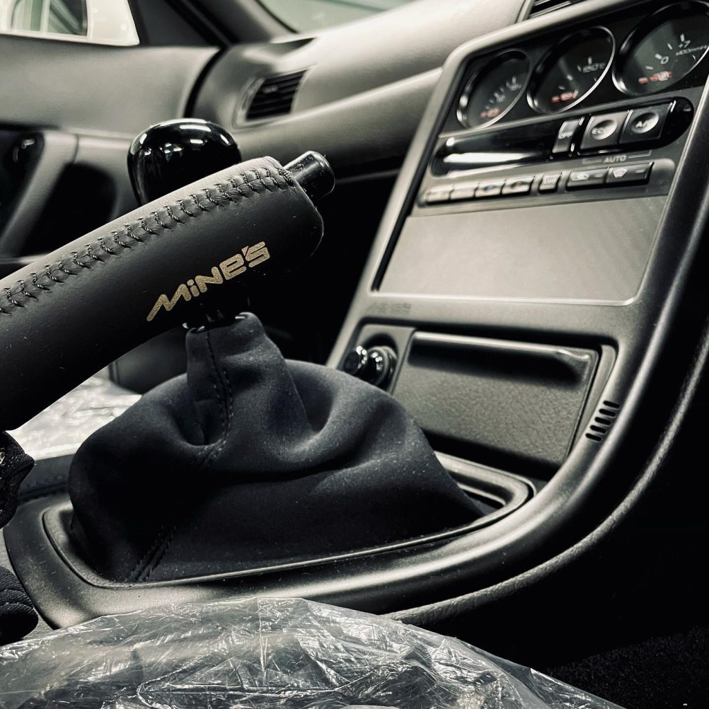 A close-up look at the Built by Legends Nissan R32 Skyline GT-R restomod's Mine's handbrake, shifter, and center console