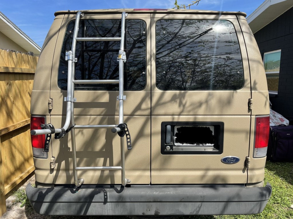 rear view of the ladder and bike rack of a tan ford e350 camper van