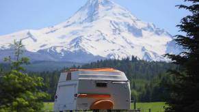 The American Dream trailer parked in a meadow with snowcapped mountains behind