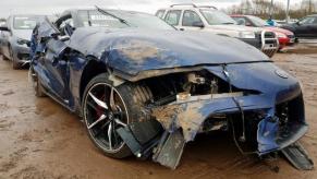 An image of a damaged Toyota Supra in an open lot.