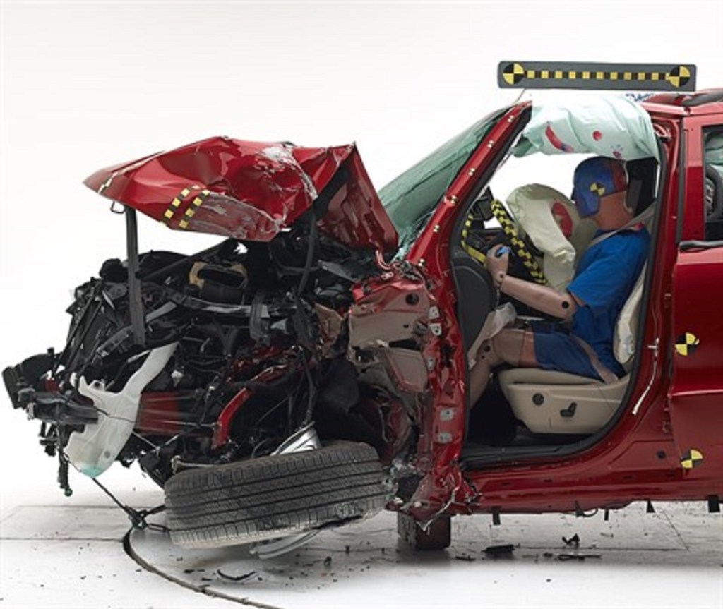 A red Dodge Durango is smashed in the front during an IIHS crash test.