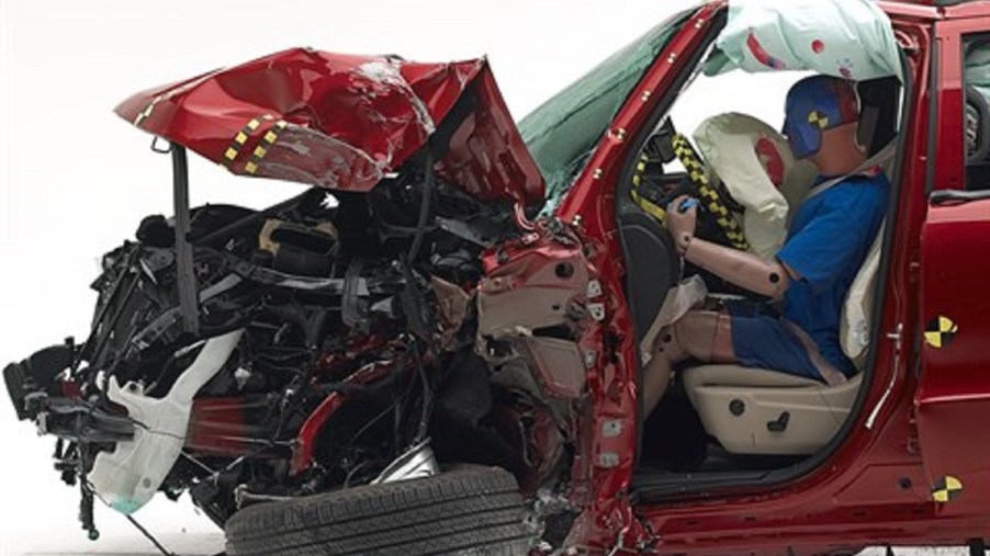 A red Dodge Durango is smashed in the front during an IIHS crash test.