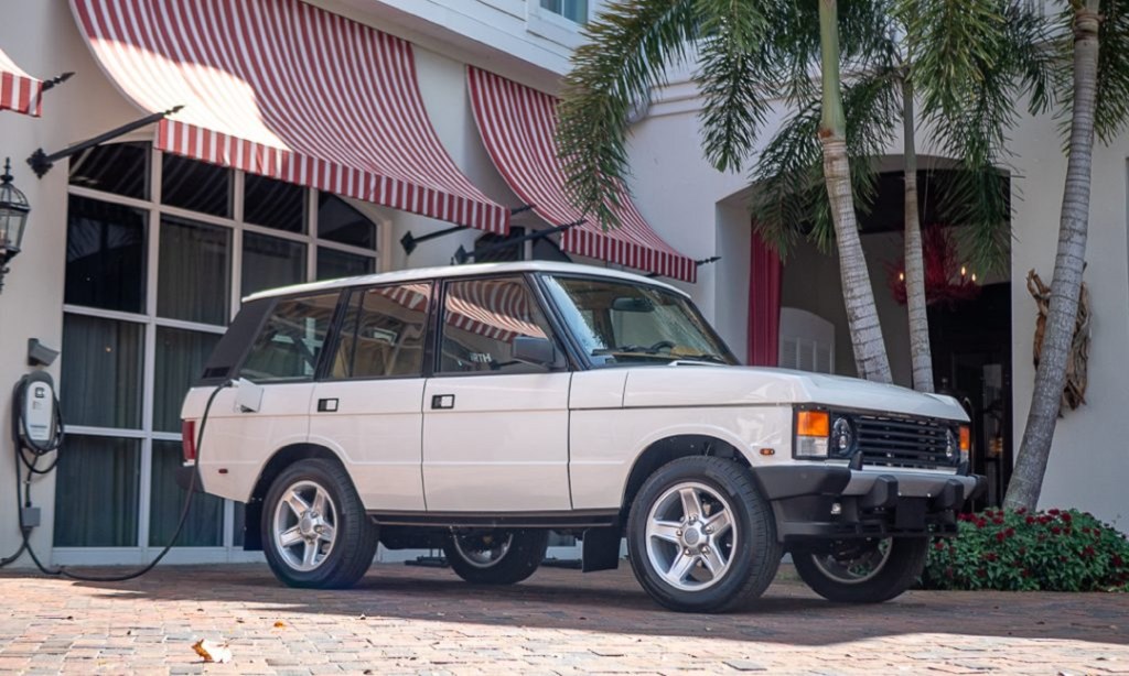 The white ECD Automotive Design electric Range Rover Classic plugged into a charger by a white building