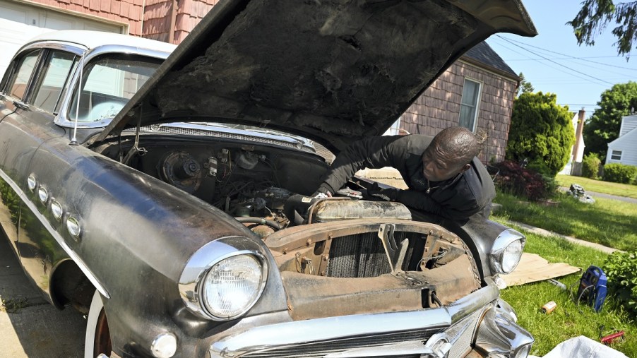 A man fixes an old car's engine.