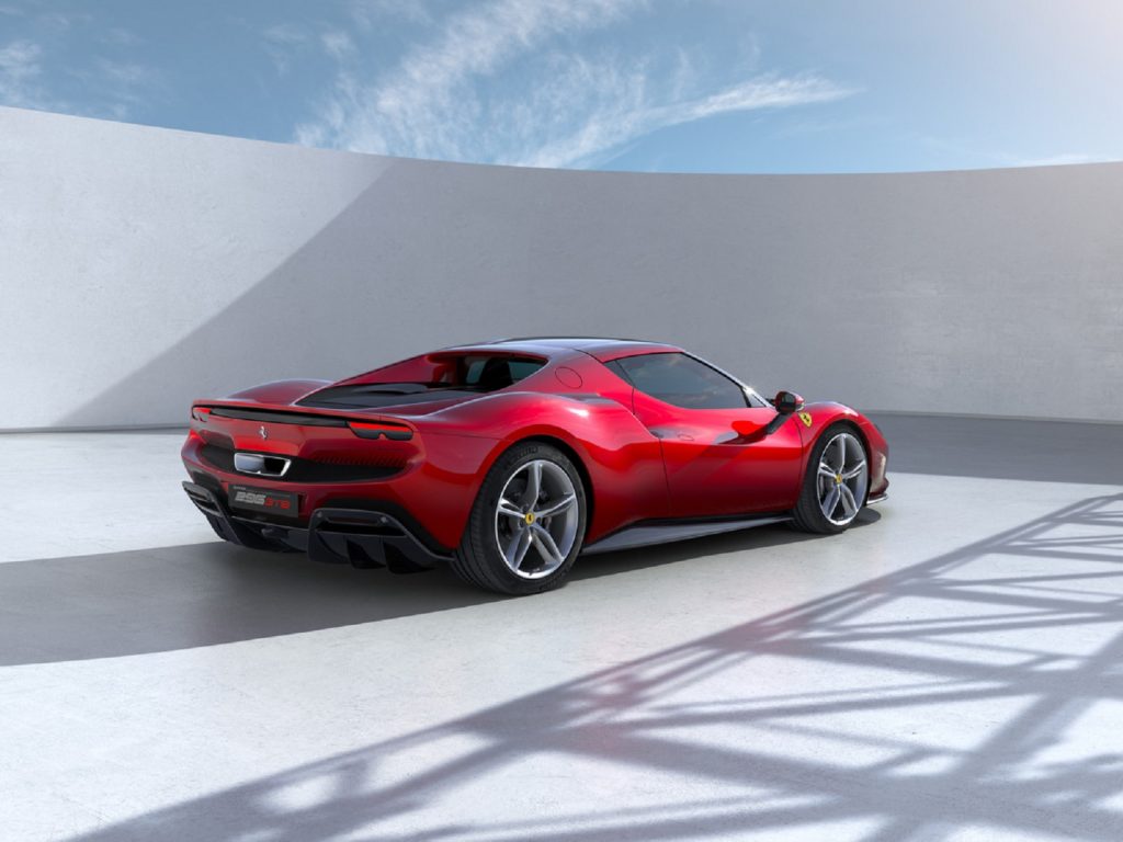 The rear 3/4 view of a red Ferrari 296 GTB by a white wall