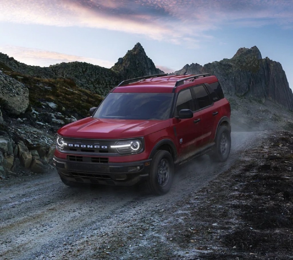 A red 2021 Ford Bronco Sport crossover drives through the mountains. 