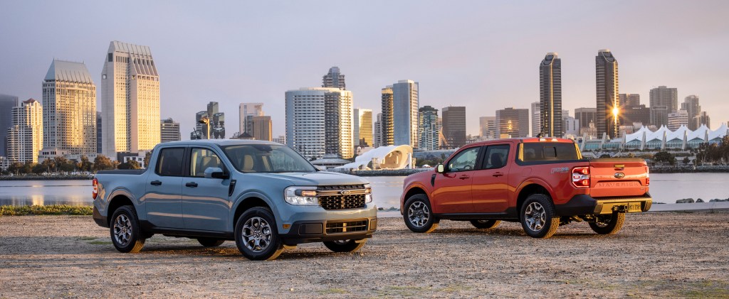 2022 Ford Maverick Hybrid XLT and 2L-EcoBoost AWD Lariat pickup truck pair parked with a skyline view. 