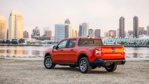an orange ford maverick parked on the beach with a skyline background