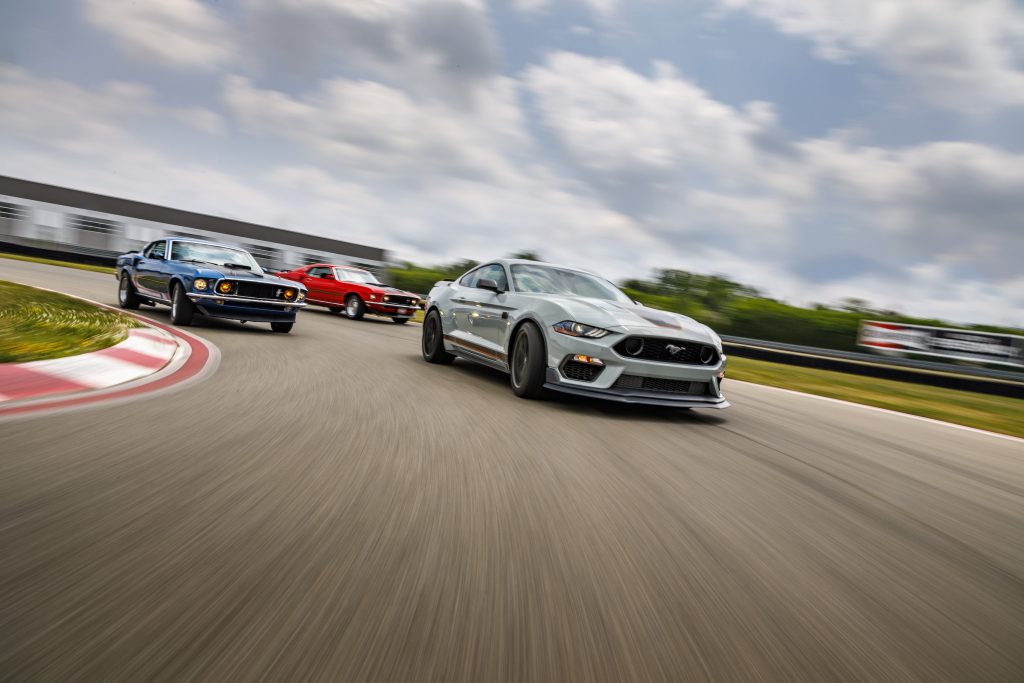 A white 2021 Ford Mustang Mach 1 on the track with older versions of the model