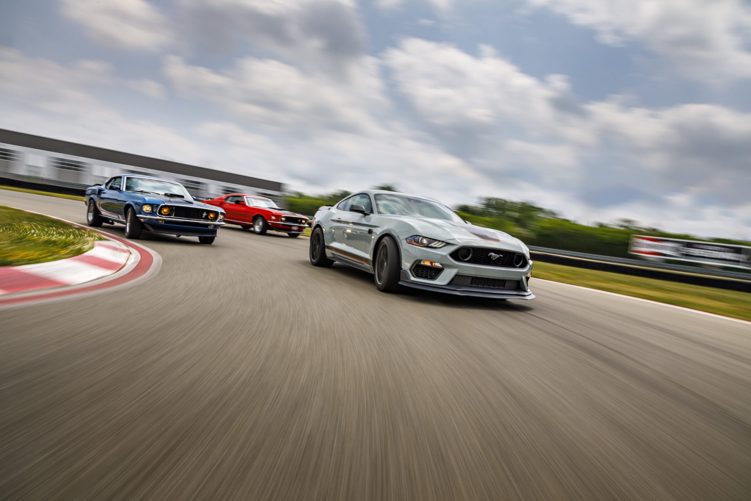 A white 2021 Ford Mustang Mach 1 on the track with older versions of the model