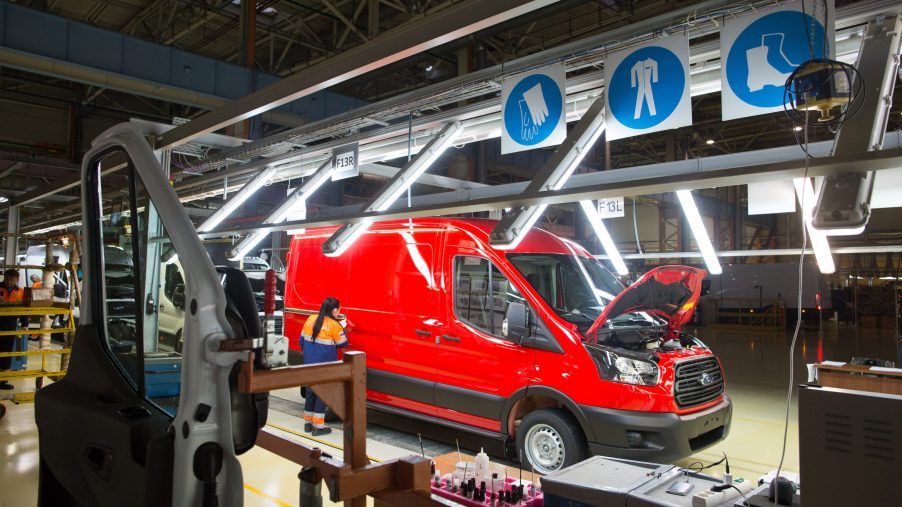 A worker performs a quality control check on a red Ford Transit van inside a light tunnel at the Ford Sollers production plant in Elabuga, Russia