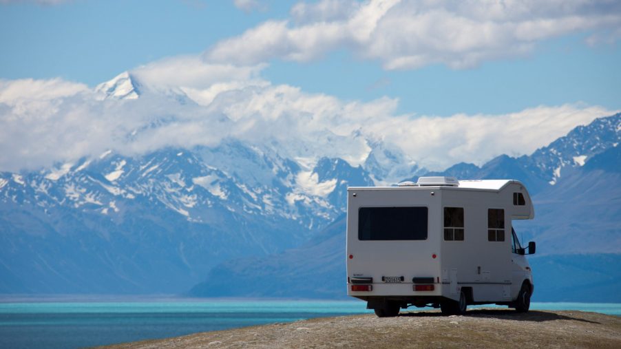 A white RV parked next to a bright blue mountain lake