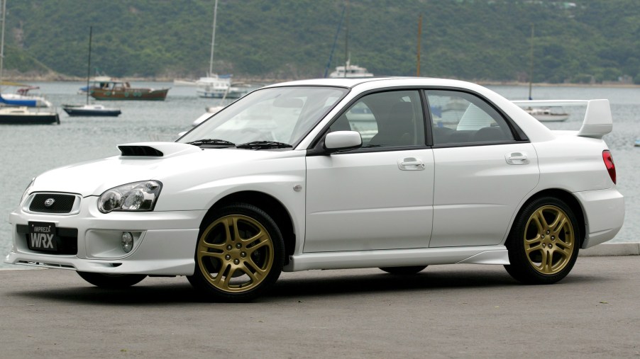A white Subaru WRX with gold wheels and spoiler