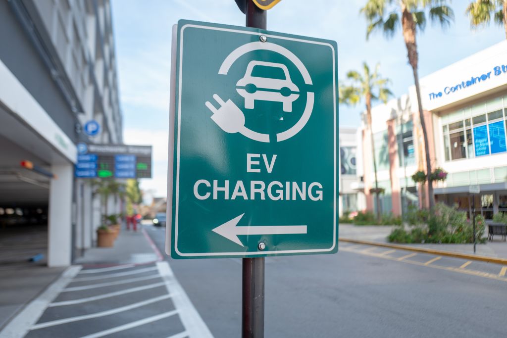 A green sign with white text indicating EV charging availability. 