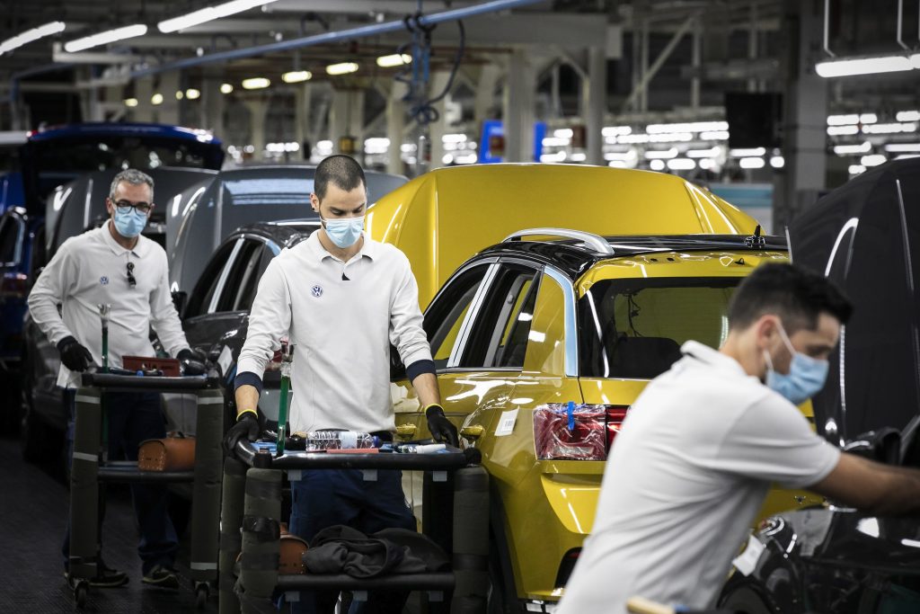 Men in a Volkswagen plant work on an assembly line