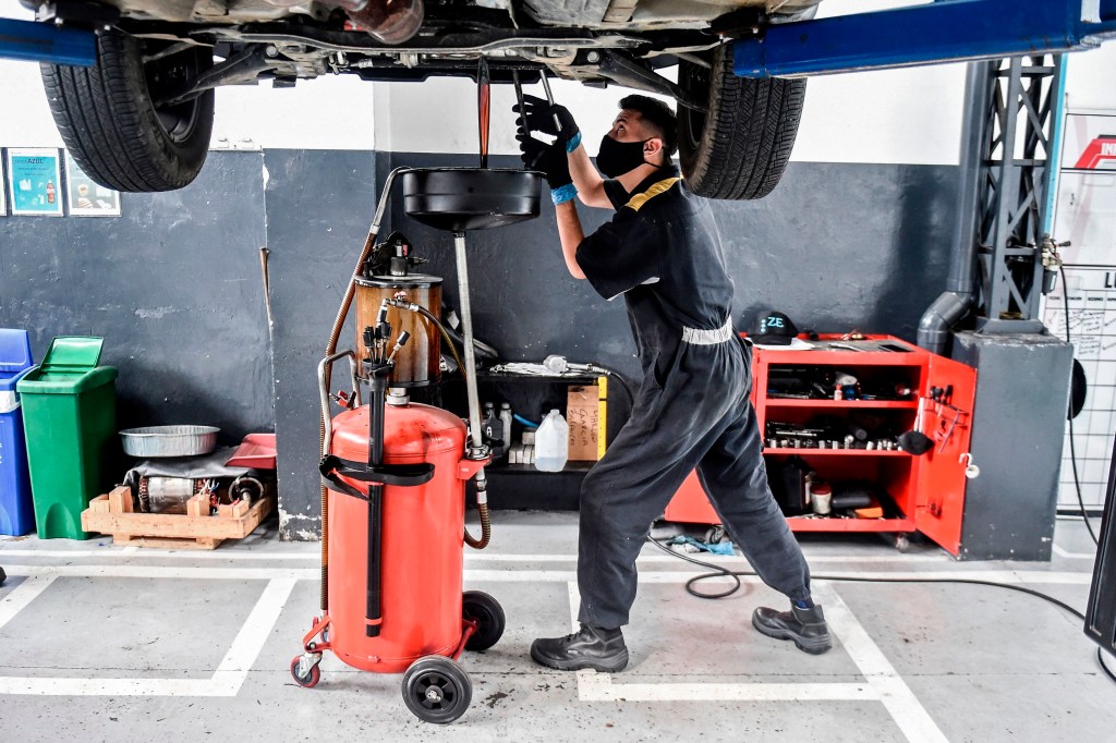 A mechanic performs an oil change in a shop