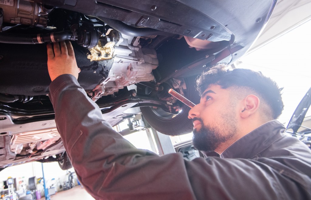A mechanic inspects the transmission of a car, often a point of inspection during a pre-purchase inspection