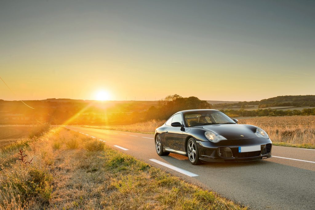A black Porsche 911 photographed at sunset