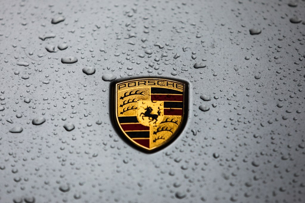 A Porsche badge, wet from the rain