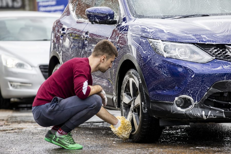 A man washes a blue car