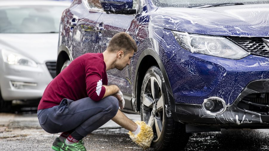A man washes a blue car