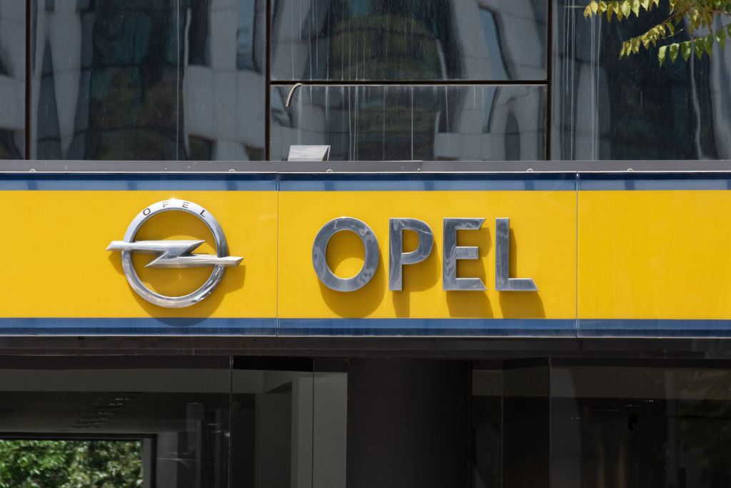 The logo of Opel hangs above a dealership on a yellow background