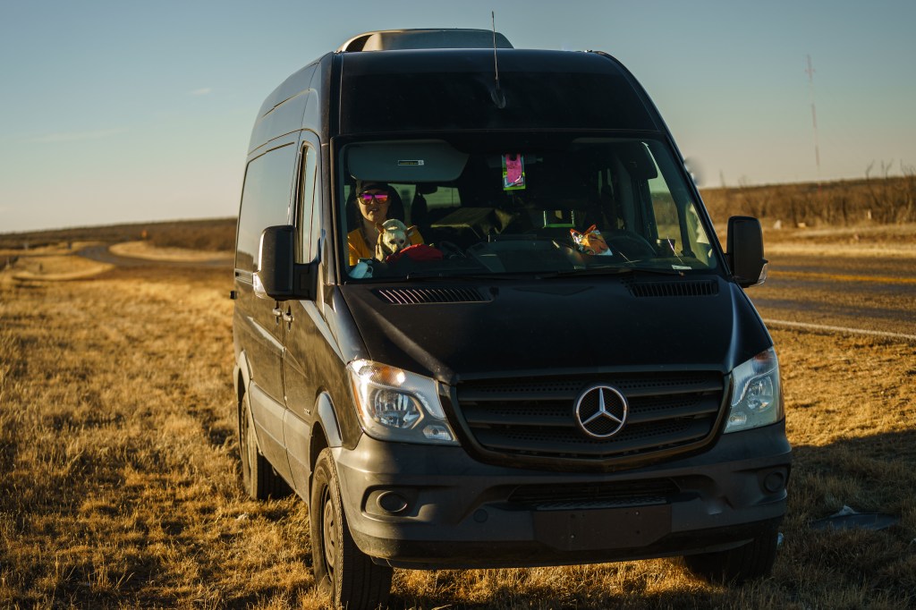 a black Mercedes Sprinter camper van driving off-road 
