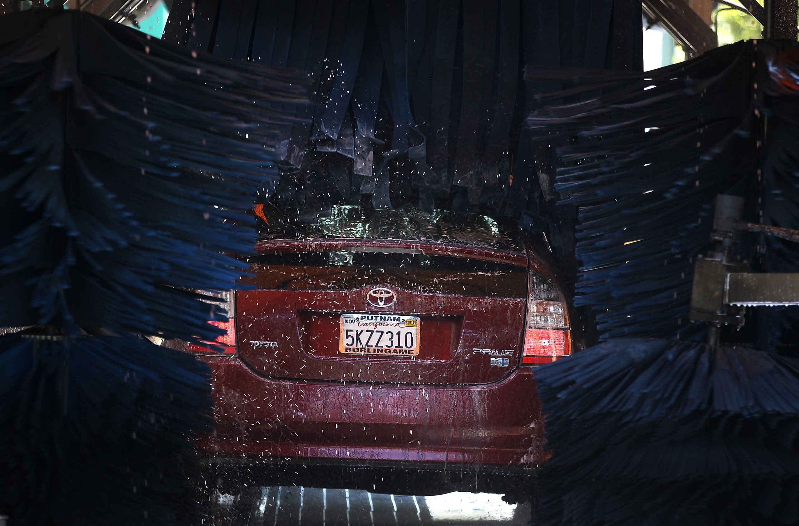 A maroon Toyota Prius goes through an automatic car wash