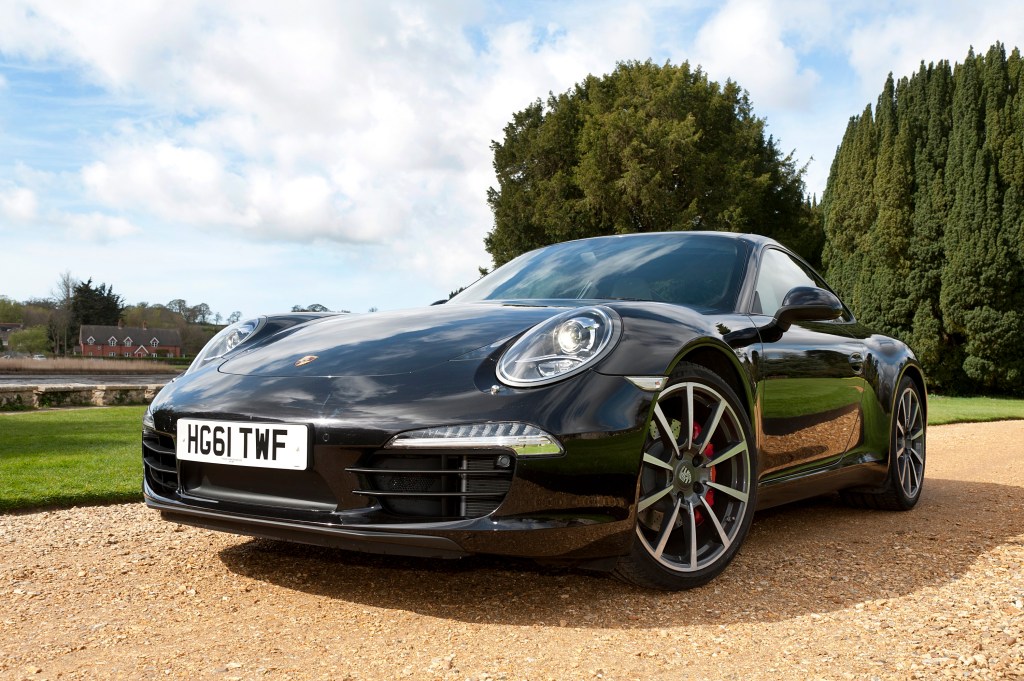 A black Porsche 911 sits on a gravel driveway